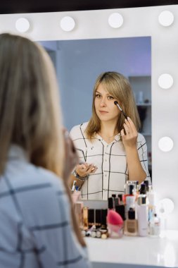 Kusursuz bir görünüm için parlak ışıklarla makyaj yapan bir kadın. Yüksek kalite fotoğraf