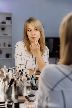 Makyaj istasyonunda ışıklı aynayla ruj süren zarif bir kadın. Yüksek kalite fotoğraf