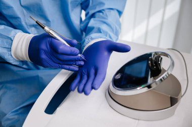 Diş hekimi, dişçi prosedürü hazırlıkları sırasında steril eldiven üzerinde hassas bir alet kullanıyor. Yüksek kalite fotoğraf