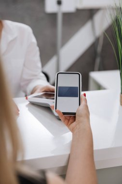 Nakitsiz işlemler için modern klinik resepsiyonunda akıllı telefonlu güvenli bir cep telefonu ödemesi. Yüksek kalite fotoğraf