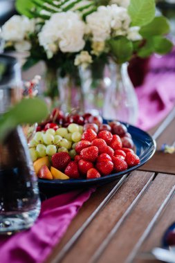 Masada çilekli, üzümlü ve şeftalili taze meyve tabağı, yaz etkinlikleri için mükemmel. Yüksek kalite fotoğraf