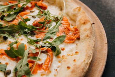 Lezzetli bir yemek için somon füme, roka ve ahşap bir tahtanın üzerinde kapari ile gurme pizza. Yüksek kalite fotoğraf