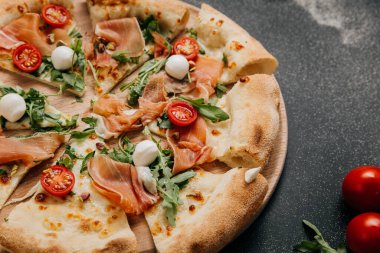 Lezzetli prosciutto ve roka pizzası, kiraz domatesli ve ahşap tabakta mozzarella. Yüksek kalite fotoğraf