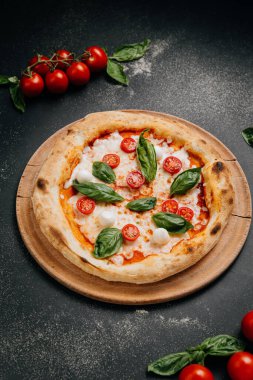 Çeri domatesli klasik Margherita pizzası, mozzarella ve ahşap tabakta taze fesleğen. Yüksek kalite fotoğraf