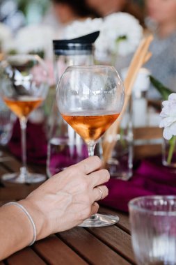 Elegant hand holding a glass of rose wine, surrounded by vibrant table decor at a festive gathering. High quality photo clipart