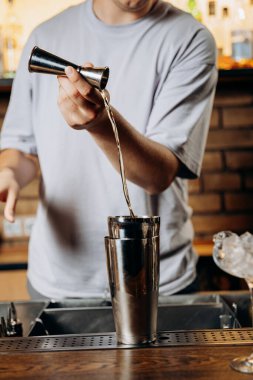 Barmen bardağa likör dolduruyor, kokteyl hazırlığında ustalık ve hassasiyet gösteriyor. Yüksek kalite fotoğraf