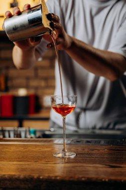 Barmen bardağa canlı kırmızı kokteyl dolduruyor. Karışımsal zarafet ve hassasiyet sergiliyor. Yüksek kalite fotoğraf