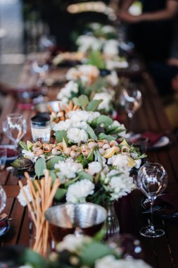 Zarif bir kutlama için çiçekli, aperatifli ve şarap kadehli lüks yemek masası. Yüksek kalite fotoğraf