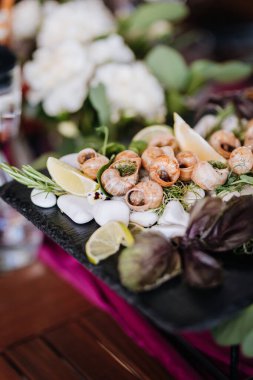 Taze otlar ve limonlu salyangoz tabağı, servis tahtasında zarif bir şekilde sunuluyor. Yüksek kalite fotoğraf