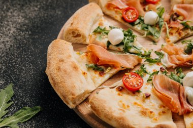 Lezzetli prosciutto ve roka pizzası, kiraz domatesli ve ahşap tabakta mozzarella. Yüksek kalite fotoğraf