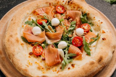 Prosciutto, mozzarella, roka ve kiraz domatesli gurme pizza. Yemek severler için mükemmel bir ziyafet. Yüksek kalite fotoğraf