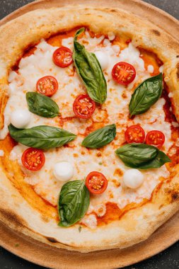 Taze fesleğenli Margherita pizza, mozzarella ve kırsal ahşap tabakta vişneli domates. Yüksek kalite fotoğraf