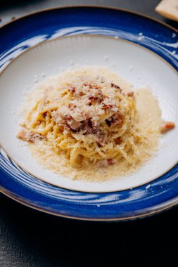 Klasik İtalyan Carbonara makarnası. Parmesan ve krema soslu zarif mavi bir tabakta servis ediliyor. Yüksek kalite fotoğraf