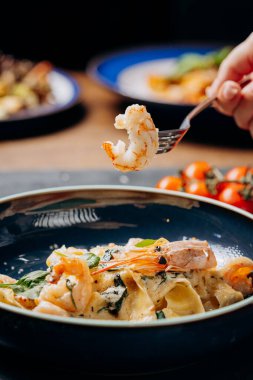 Mükemmel pişmiş bir karidesi kremalı makarna yemeğinden çatalla kaldırmak, enfes bir deniz ürünleri düşkünlüğü. Yüksek kalite fotoğraf