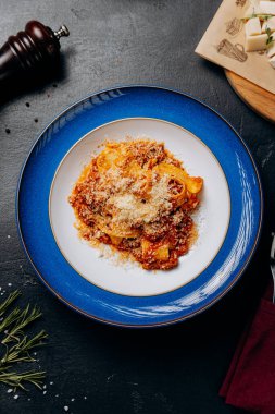 Geleneksel İtalyan bolonez makarnası, üzerinde parmesan peyniri olan zarif bir mavi tabakta servis edilir. Yüksek kalite fotoğraf