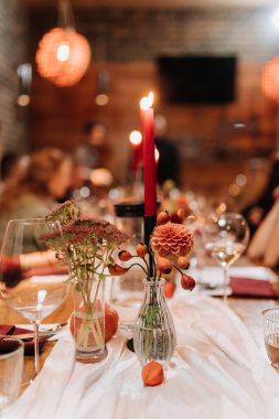 Şenlikli bir akşam yemeğinde kırmızı mumları, çiçekleri ve cam süslemeleri olan zarif masa süsü. Yüksek kalite fotoğraf