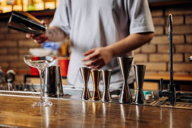Barmen şık bir bar ortamında jigger ve cam eşyalar ile bir içki hazırlıyor. Yüksek kalite fotoğraf