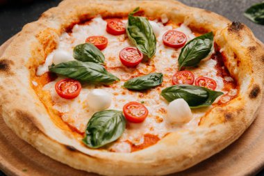 Çeri domatesli klasik Margherita pizzası, mozzarella ve ahşap tabakta taze fesleğen. Yüksek kalite fotoğraf