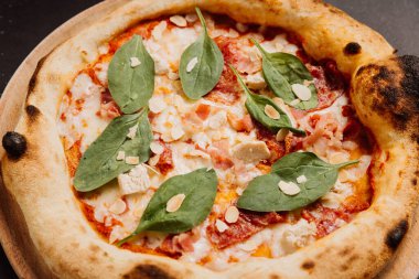 Tahta tabakta ıspanaklı, bademli ve taze domatesli lezzetli gurme pizza. Yüksek kalite fotoğraf