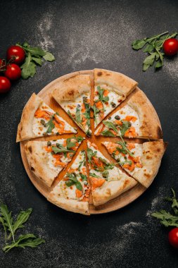 Dilimlenmiş gurme pizza füme somon, roka ve ahşap bir tahtanın üzerinde kapari. Yüksek kalite fotoğraf