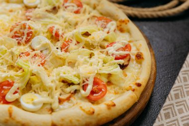 Kiraz domatesli Sezar salatalı pizza, bıldırcın yumurtası, marul ve parmesan, ahşap bir tahtanın üzerinde servis edilir. Yüksek kalite fotoğraf