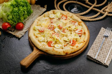 Kiraz domatesli Sezar salatalı pizza, bıldırcın yumurtası, marul ve parmesan, ahşap bir tahtanın üzerinde servis edilir. Yüksek kalite fotoğraf