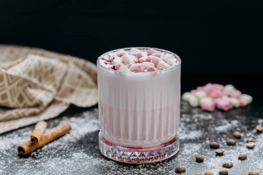 Cup of pink hot chocolate with marshmallows and powdered sugar on a rustic dark background. High quality photo clipart