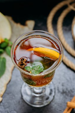 Narenciyeli, tarçınlı ve bardakta nane aromalı, koyu kırsal bir zemin üzerine kurulmuş bir bitki çayı. Yüksek kalite fotoğraf