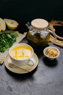 Bardakta armut ve nane çayı, cam çaydanlık, taze malzemeler ve siyah masada şeker küpleri. Yüksek kalite fotoğraf
