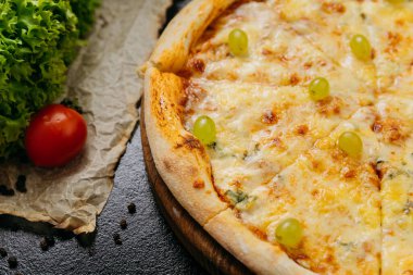Dört peynirli yeşil üzümlü gurme pizza, şık bir restoran ortamında ahşap tahtada servis ediliyor. Yüksek kalite fotoğraf