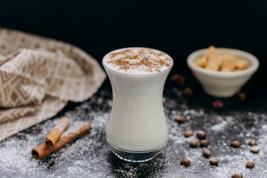 Tarçın ve hindistan cevizi gevreğiyle kaplanmış şık bir bardakta kremalı süt içeceği. Yüksek kalite fotoğraf
