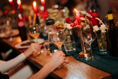 Çiçek desenli mum ışığında akşam yemeğinde şarap kadehini tutan zarif bir el. Yüksek kalite fotoğraf