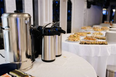 Sıcak içecek dağıtıcılarıyla servis masası ve davetliler için çeşitli sandviçler. Yüksek kalite fotoğraf