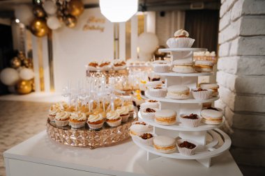 Lüks altın tepsilerdeki beyaz kremalı kurabiyelerin olduğu zarif bir tatlı masası. Yüksek kalite fotoğraf