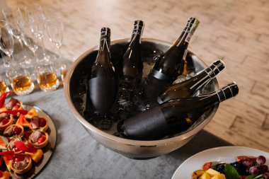 Buz kovasında soğutulmuş şampanya şişeleri, bardaklar ve masada nefis parti atıştırmalıkları. Yüksek kalite fotoğraf