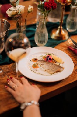 Gurme balık tabağı, şarap kadehi ve şenlikli sofra düzeniyle şık bir restoran yemeği. Yüksek kalite fotoğraf