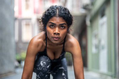 Güçlü atletik Afrikalı kadın koşucunun yakın plan yüzü. Gözü morarmış bir kadın konsantre oluyor. Spor kıyafetlerini giyerek şehrin arka planında koşmak. Spor ve spor motivasyonu. Çalıştırıcı kavramı.