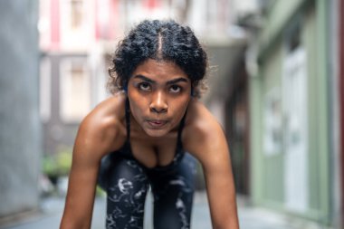 Güçlü atletik Afrikalı kadın koşucunun yakın plan yüzü. Gözü morarmış bir kadın konsantre oluyor. Spor kıyafetlerini giyerek şehrin arka planında koşmak. Spor ve spor motivasyonu. Çalıştırıcı kavramı.