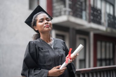 Siyahi mezuniyet elbiseli Afrikalı öğrenciler diplomayı tutuyor ve birlikte duruyorlar. Mutluluk ve zarafetle.