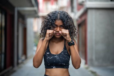 Çekici ve güçlü Afrikalı kadın açık hava sporlarından önce geriniyor. Spor konsepti. Sağlıklı bir yaşam tarzı. Kadın havadaki boksla ısınıyor..