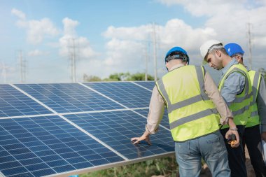 Mühendis, güneş pili paneli veya fotovoltaik hücrenin yapımını elektronik cihazla denetliyor. Yeşil enerjinin endüstriyel yenilenebilir enerjisi. Kule çatısında çalışan fabrika işçisi.
