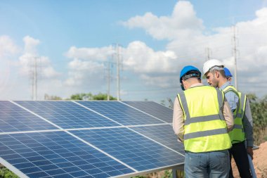 Mühendis, güneş pili paneli veya fotovoltaik hücrenin yapımını elektronik cihazla denetliyor. Yeşil enerjinin endüstriyel yenilenebilir enerjisi. Kule çatısında çalışan fabrika işçisi.