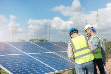 Mühendis, güneş pili paneli veya fotovoltaik hücrenin yapımını elektronik cihazla denetliyor. Yeşil enerjinin endüstriyel yenilenebilir enerjisi. Kule çatısında çalışan fabrika işçisi.