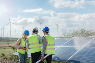 Mühendis, güneş pili paneli veya fotovoltaik hücrenin yapımını elektronik cihazla denetliyor. Yeşil enerjinin endüstriyel yenilenebilir enerjisi. Kule çatısında çalışan fabrika işçisi.