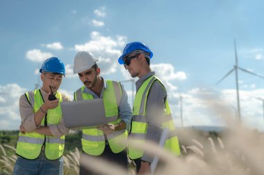 Saha görevinde çalışan Asyalı mühendis. İşçiler inşaat alanının etrafındaki inşaat ve makineleri kontrol ediyorlar. Temiz enerji ve çevresel sürdürülebilir elektrik için rüzgar türbini.