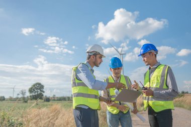 Saha görevinde çalışan Asyalı mühendisler. Çalışanlar proje alanının etrafındaki inşaat ve makineleri inceliyor. Temiz kaynak enerjisi ve çevresel sürdürülebilir rüzgar türbini elektriği.