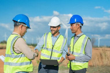 Saha görevinde çalışan Asyalı mühendisler. Çalışanlar proje alanının etrafındaki inşaat ve makineleri inceliyor. Temiz kaynak enerjisi ve çevresel sürdürülebilir rüzgar türbini elektriği.