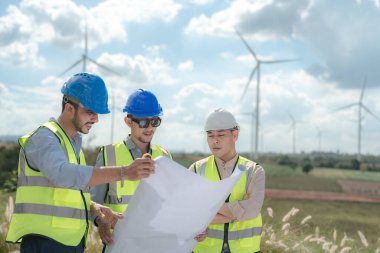 Saha görevinde çalışan Asyalı mühendis. İşçiler inşaat alanının etrafındaki inşaat ve makineleri kontrol ediyorlar. Temiz enerji ve çevresel sürdürülebilir elektrik için rüzgar türbini.