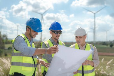 Saha görevinde çalışan Asyalı mühendis. İşçiler inşaat alanının etrafındaki inşaat ve makineleri kontrol ediyorlar. Temiz enerji ve çevresel sürdürülebilir elektrik için rüzgar türbini.