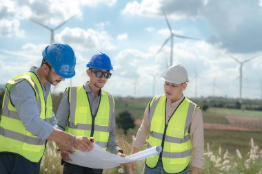 Saha görevinde çalışan Asyalı mühendis. İşçiler inşaat alanının etrafındaki inşaat ve makineleri kontrol ediyorlar. Temiz enerji ve çevresel sürdürülebilir elektrik için rüzgar türbini.